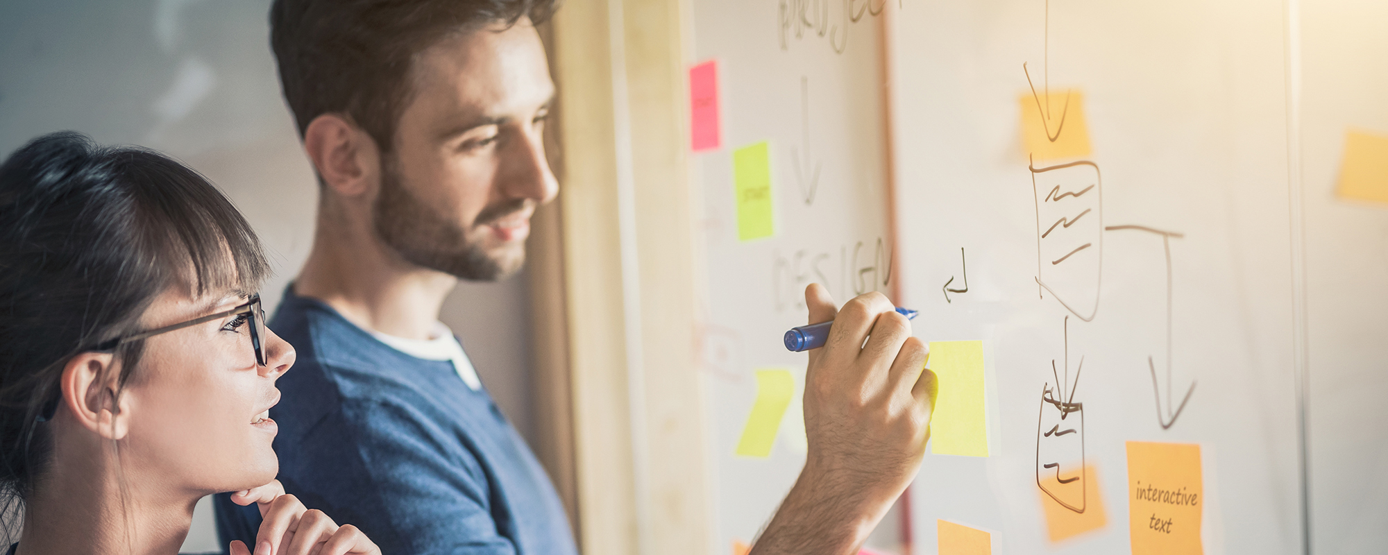 A man an woman studying a whiteboard